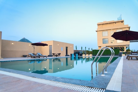 Una piscina al aire libre, sombrillas, sillones reclinables de piscina