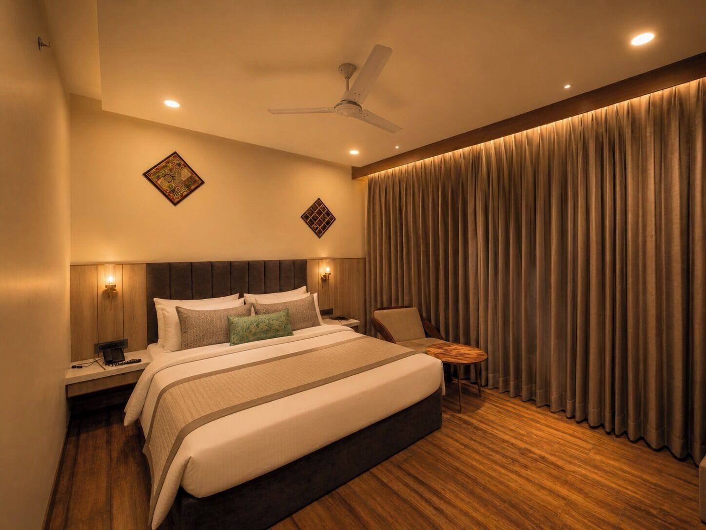 Una camera d'albergo moderna con un letto grande, una ventola a soffitto e vista sulla città attraverso le tende.
