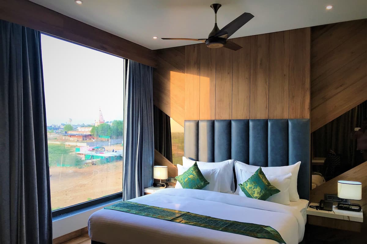 A modern hotel room with a large bed, a ceiling fan, and a view of the outside.