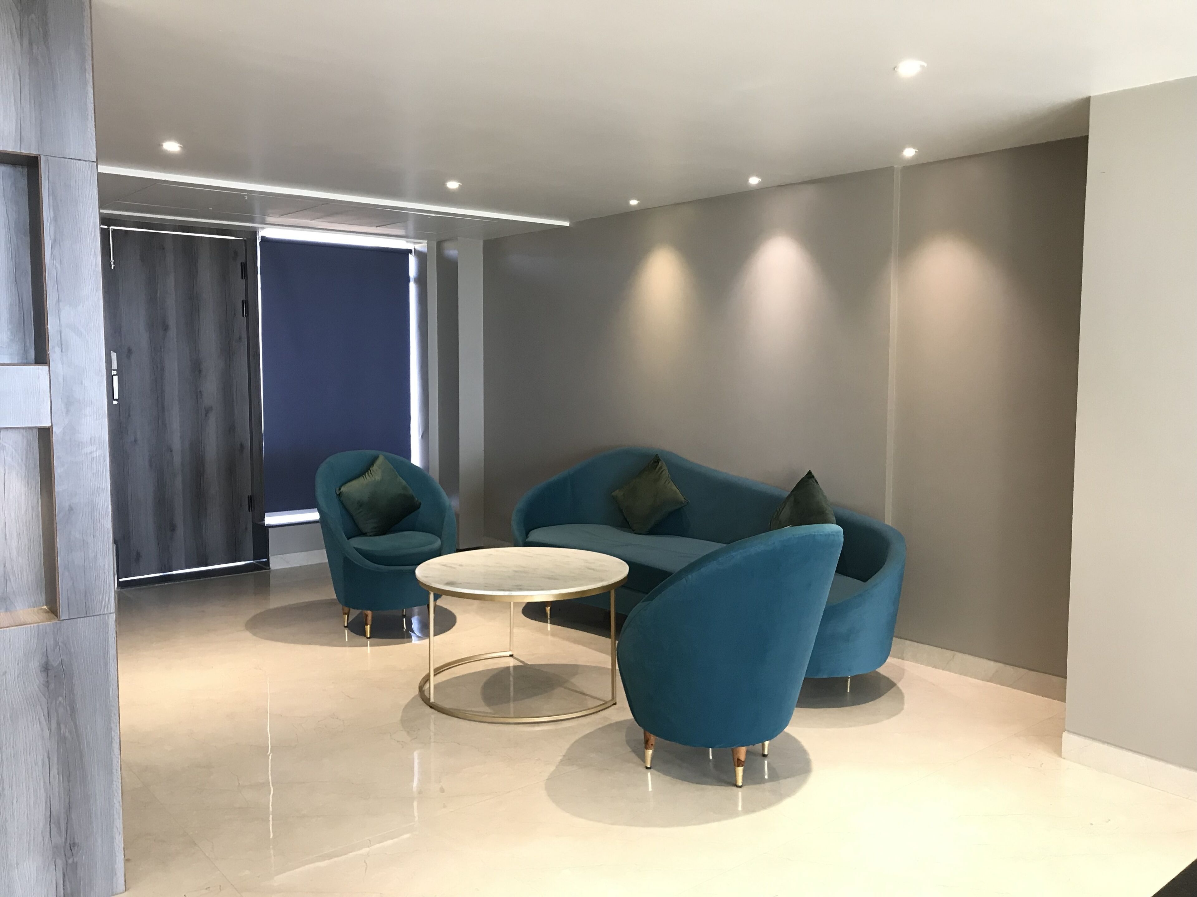 A modern room with a blue sofa, two matching armchairs, and a round coffee table.
