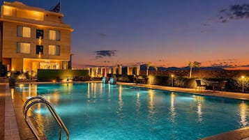 Una piscina al aire libre, sombrillas, sillones reclinables de piscina