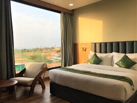 Una habitación de hotel con una cama grande, una silla y vista a la ciudad.