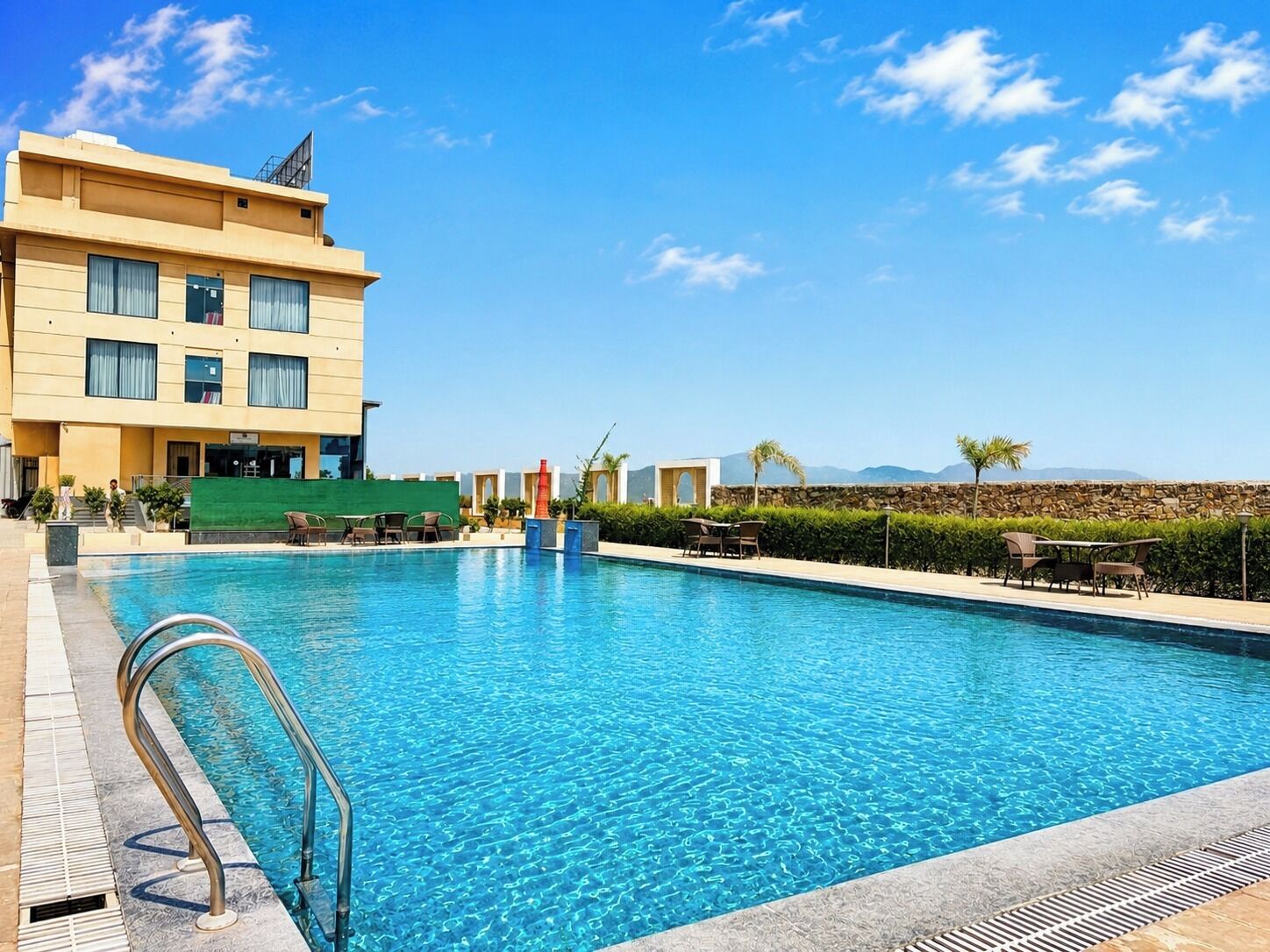 Un hotel con piscina, zona de estar al aire libre y vistas a las montañas.