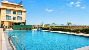 Un hotel con piscina, zona de estar al aire libre y vistas a las montañas.