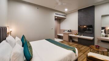 A modern hotel room with a large bed, a small desk, a vanity, and a television.