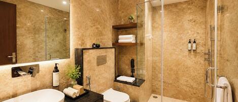 Un bagno moderno con un ampio specchio, due lavabi, un water, cabina doccia in vetro e un piccolo ripiano con asciugamani e articoli da toilette.