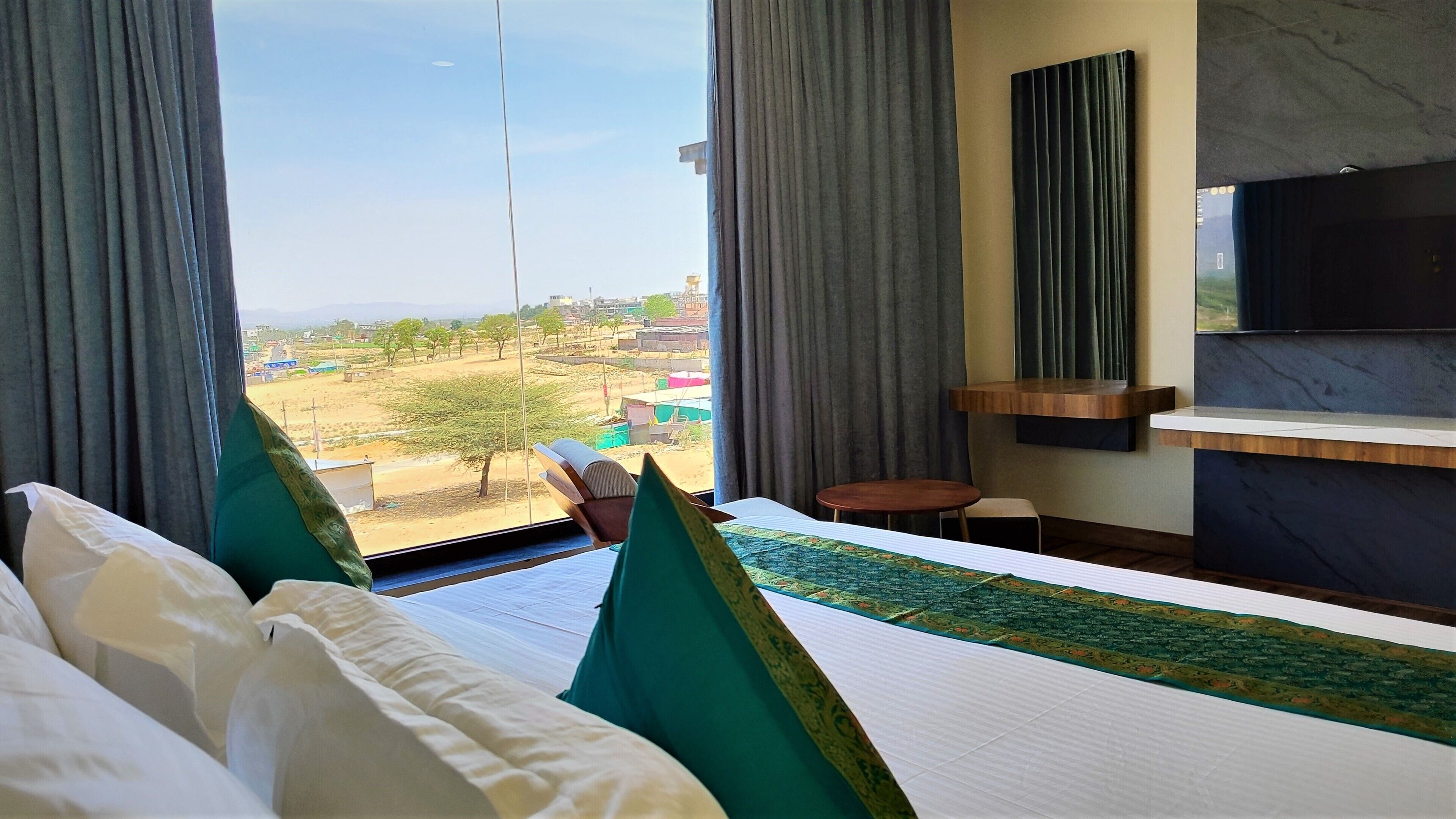 Camera d'albergo con un letto, un tavolino, una TV a parete e vista sul paesaggio esterno.