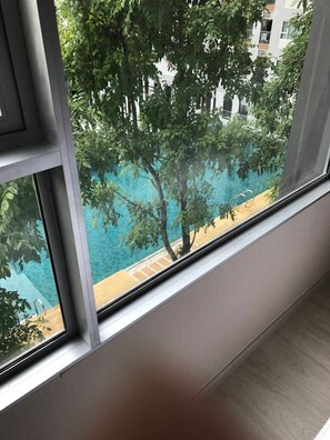 Ein Fenster mit Blick auf einen Pool und Bäume.