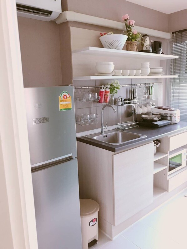 A modern kitchen with a built-in refrigerator, a stainless steel sink, and a countertop with a kettle and a rice cooker.