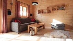 En ombonad träinredning med en soffa, ett litet bord och ett husdjur som ligger på en matta.