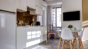 A modern kitchen with white cabinets, a built-in oven, and a dining area with a table and chairs. - Palacete da Baixa, Studio Superior appartment (Faro)