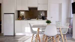 A modern kitchen with white cabinetry, a stainless steel range hood, and a dining area with a white table and chairs. - Palacete da Baixa, Studio Superior appartment (Faro)