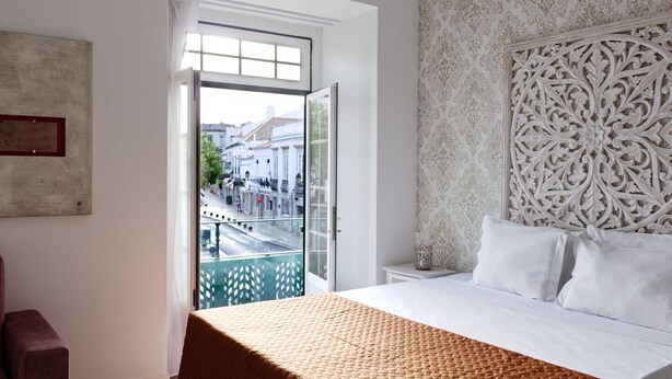 A hotel room with a large bed, a view of the street through an open door, a patterned headboard, and a small bedside table. - Palacete da Baixa, Studio Superior appartment (Faro)