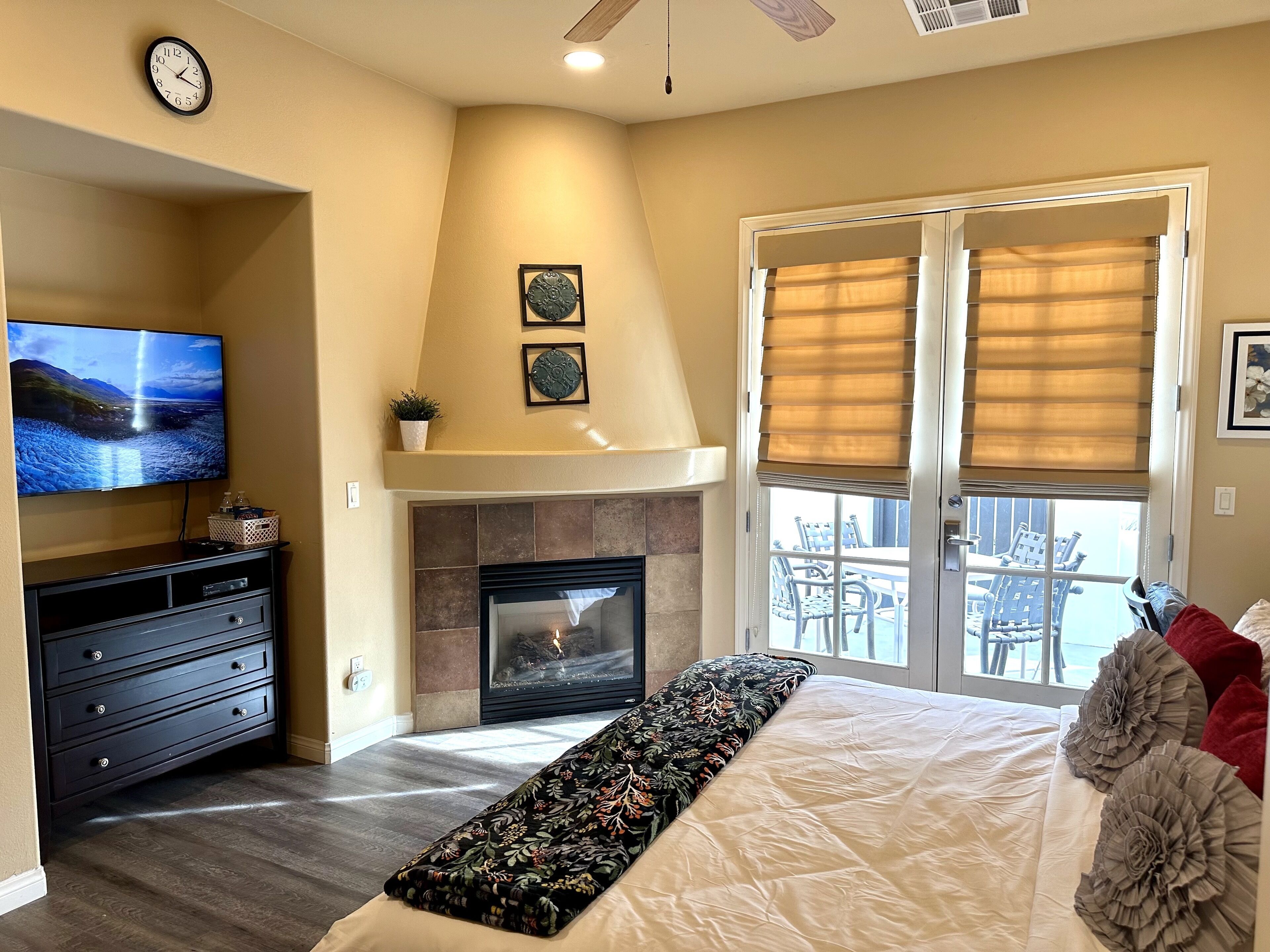 A bedroom with a fireplace, a television, and a balcony with outdoor furniture.