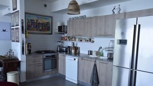 A modern kitchen with wooden cabinets, a stainless steel refrigerator, and a fruit bowl on the counter.
