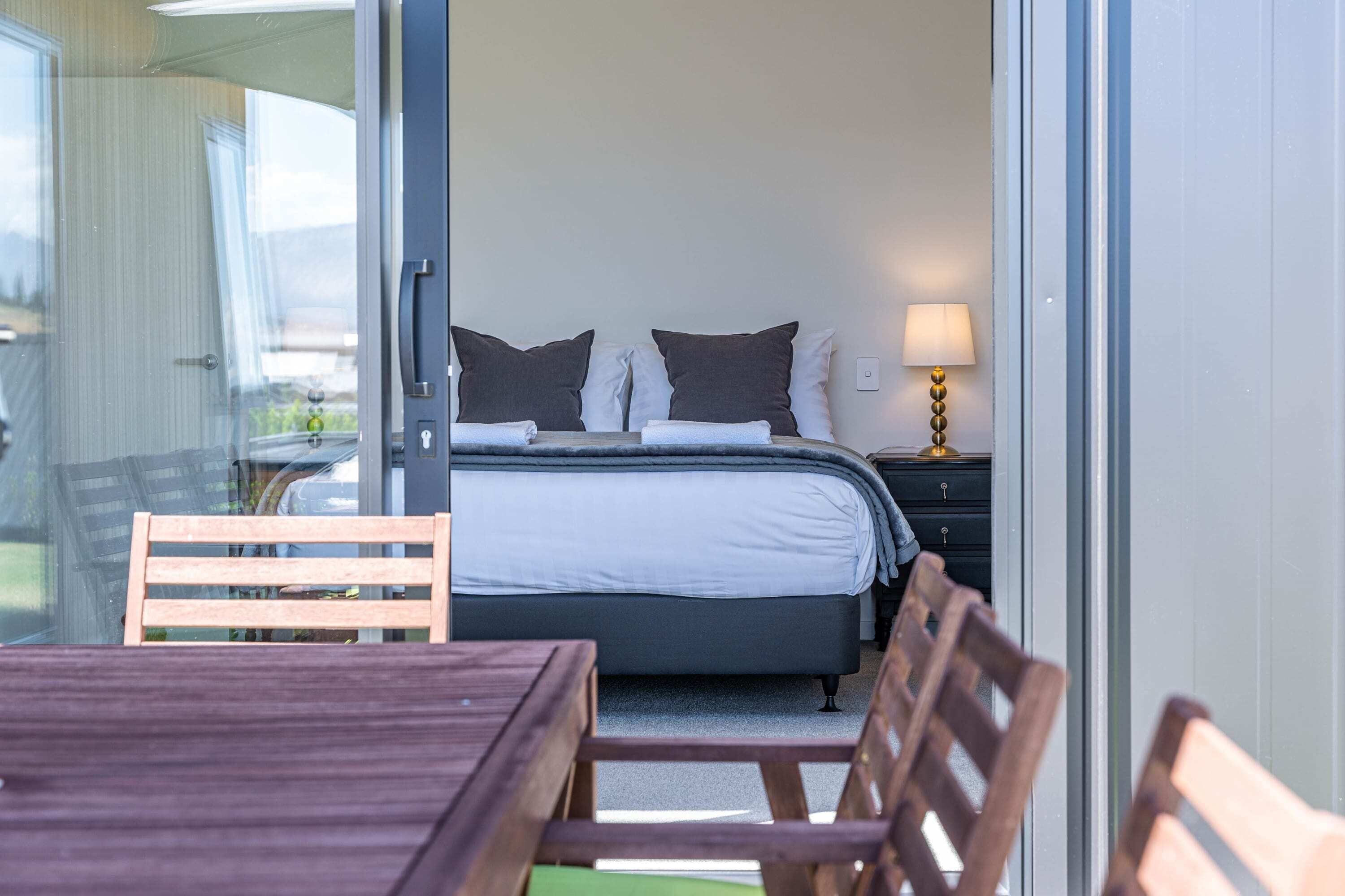 A bedroom with a bed, pillows, a nightstand, and a lamp.