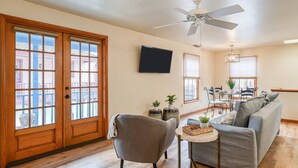 A living room with a grey sofa, a small round table, and a ceiling fan. - Heart of Historic District! Rooftop with Fire Pit, Park and Walk Everywhere, $300 in Free Tickets! (St. Augustine)