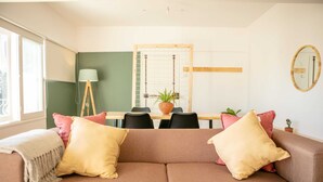 En stue med en brun sofa, et spisebord med stole, en lampe og en potteplante.