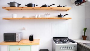 A kitchen with wooden shelves, a gas stove, a microwave, and a toaster. - Maison Moz - Maputo View III (Maputo)
