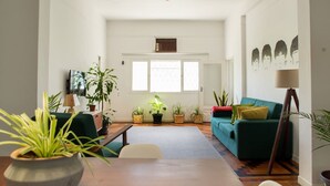Un saló espaiós amb un sofà verd, una taula de centre de fusta i diverses plantes en testos.