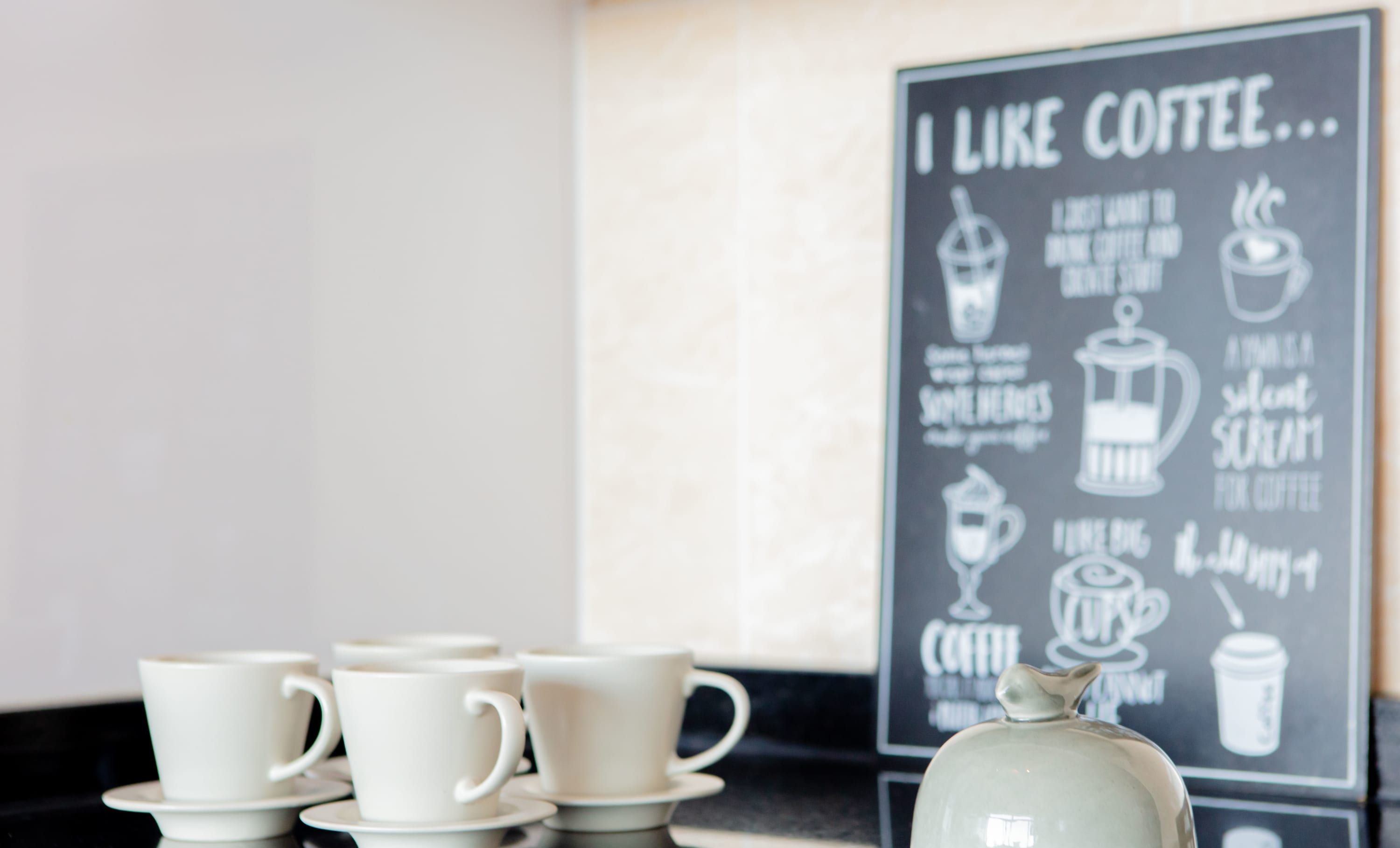 Un coin café avec des tasses blanches et une pancarte sur laquelle on peut lire : « J’aime le café… »