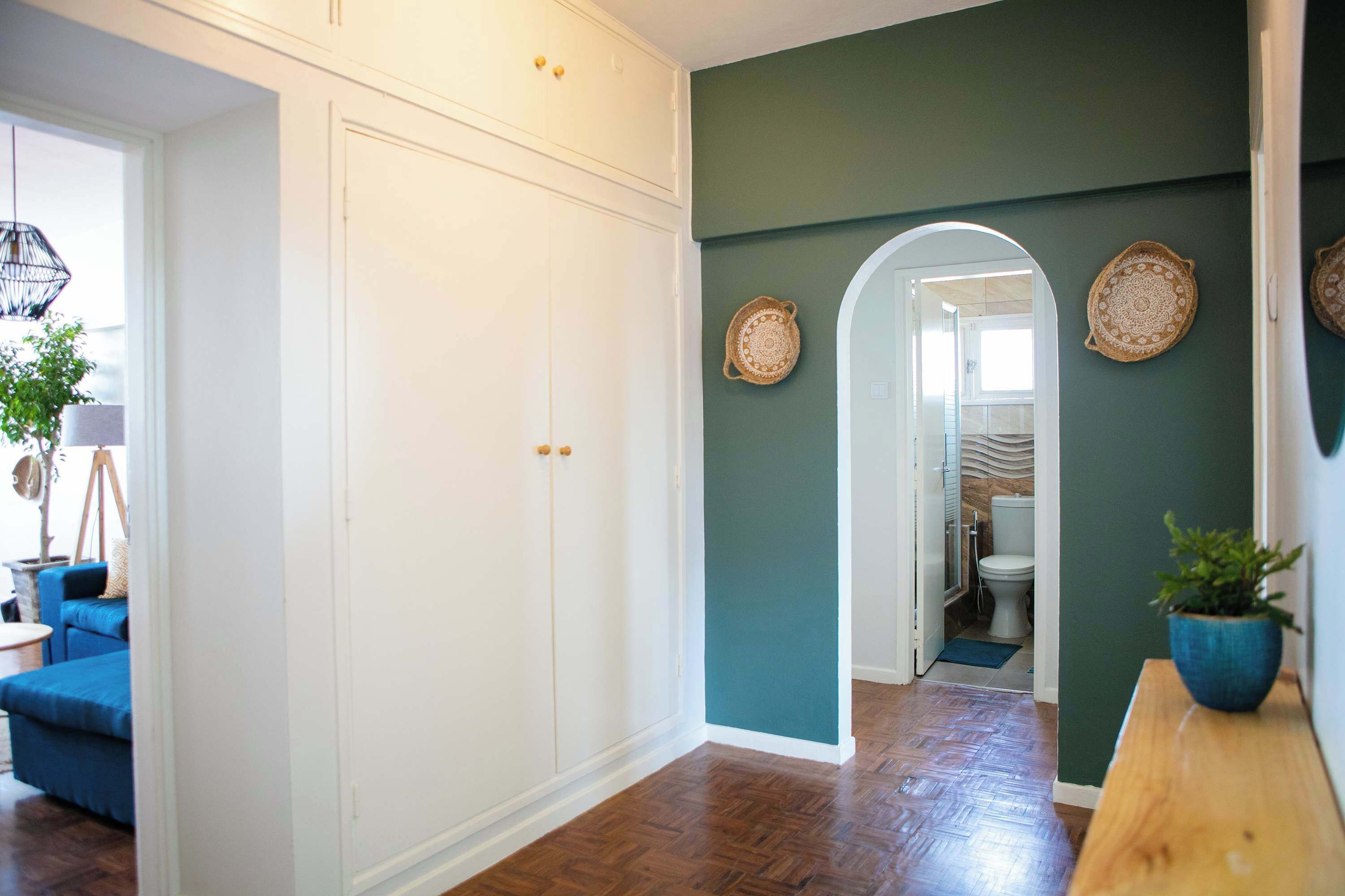 A hallway with a white wardrobe, a blue sofa, and a wooden bench.