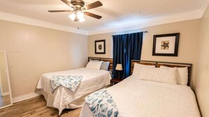 Une chambre d’hôtel avec deux lits, un ventilateur de plafond et une fenêtre avec des rideaux.