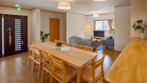 Un comedor con una mesa y sillas de madera, un sofá y un televisor al fondo.