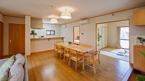 Amplia sala de estar con una mesa y sillas de madera, un sofá y un espejo grande.