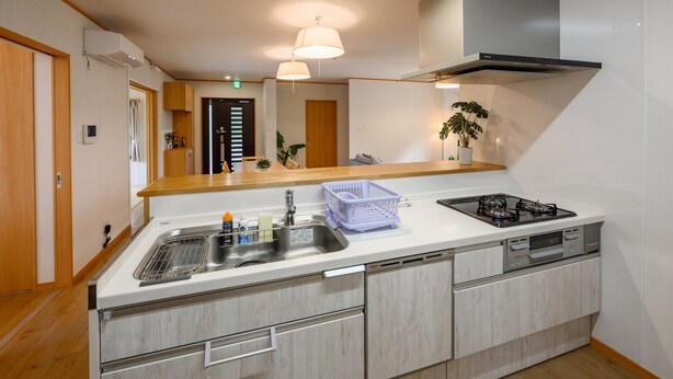Una cocina moderna con lavavajillas integrado, estufa y pileta. Se observan placares de madera y una encimera.
