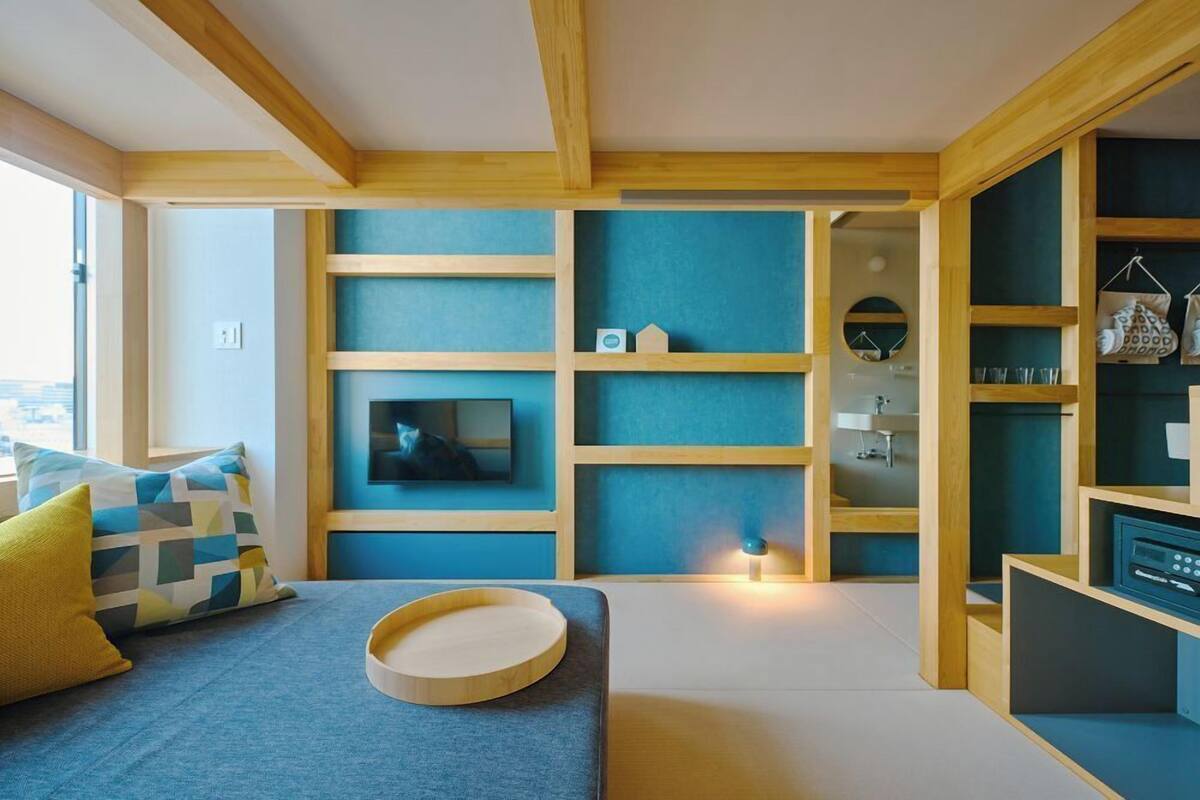 Una sala de estar moderna con televisor, estanterías de madera y un sofá con cojines.