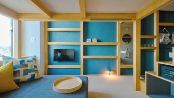 A modern living room with a TV, wooden shelves, and a sofa with cushions.