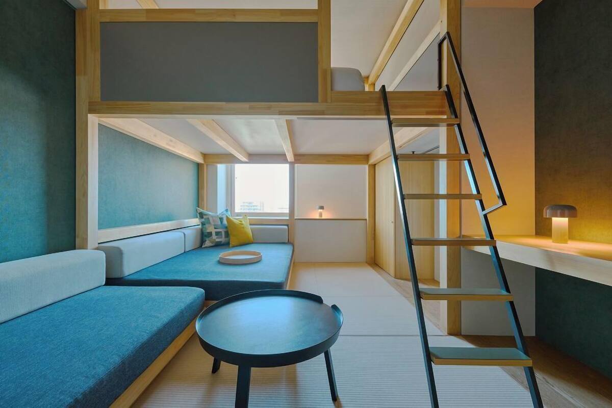 Habitación compacta con varios niveles, una cama en altillo, un sofá, una mesa pequeña y una escalera.