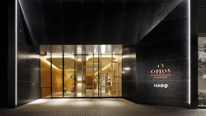 Entrada moderna de un hotel con puerta de vidrio, interior iluminado y un letrero que dice Hoshino Resorts Kumamoto.