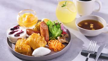 A breakfast plate with eggs, sausage, vegetables, and a drink.