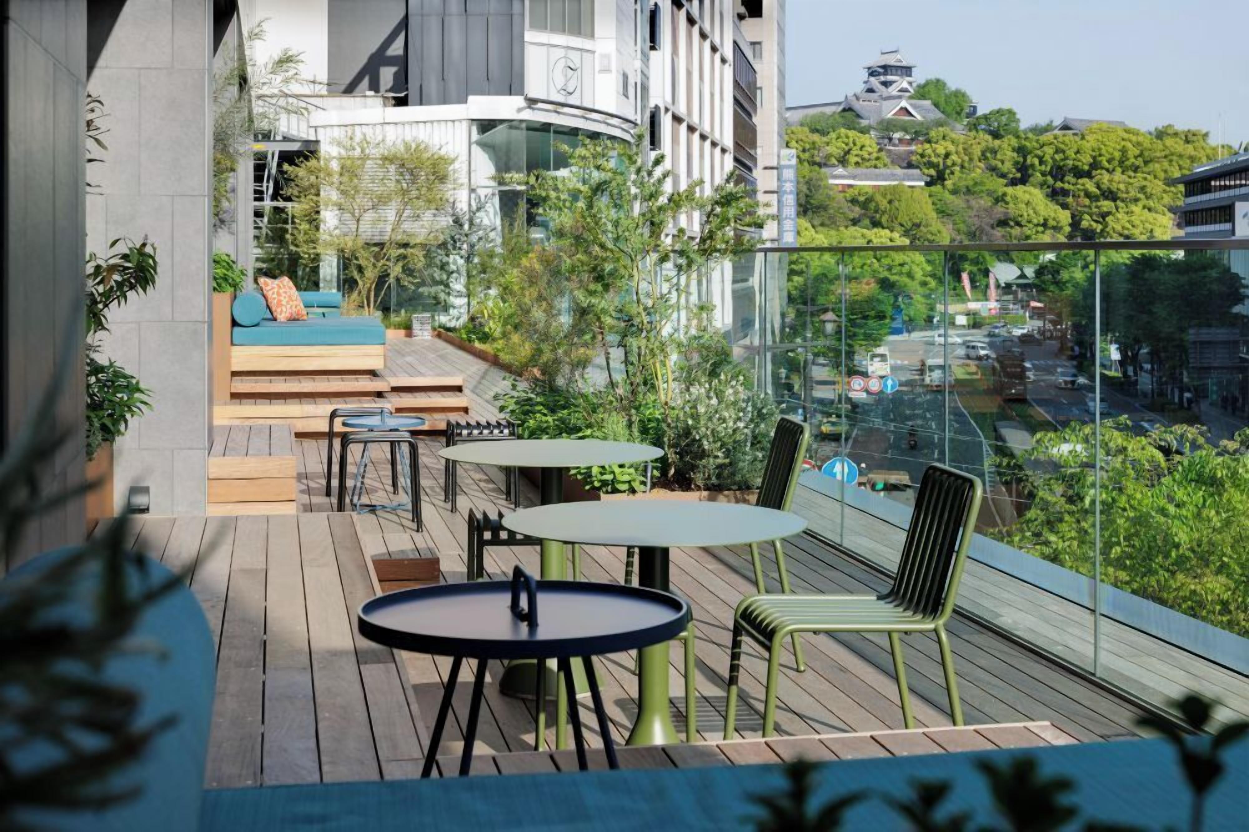 Una terraza moderna al aire libre con asientos, mesas y vista a un edificio tradicional.