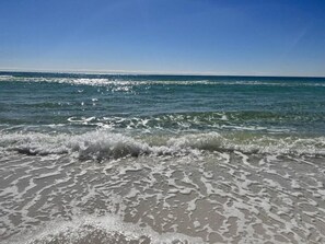 A beach with waves gently lapping onto the shore under a clear sky.