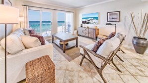 Un salón espacioso con un gran ventanal con vistas al mar, un sofá, una mesa de centro y un jarrón decorativo.