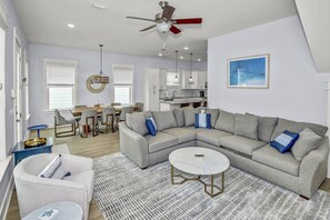 A modern living room with a sectional sofa, a round coffee table, and a dining area with a table and chairs.