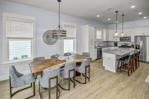 A modern kitchen with white cabinets, a central island with bar stools, and pendant lighting.