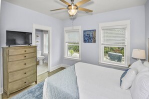 A bedroom with a bed, dresser, ceiling fan, and windows with blinds.