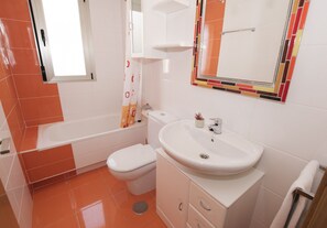 Ein Badezimmer mit Toilette, Waschbecken und Badewanne – alles in Weiß.