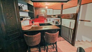 A kitchen with a central island, two bar stools, and a wooden ceiling.