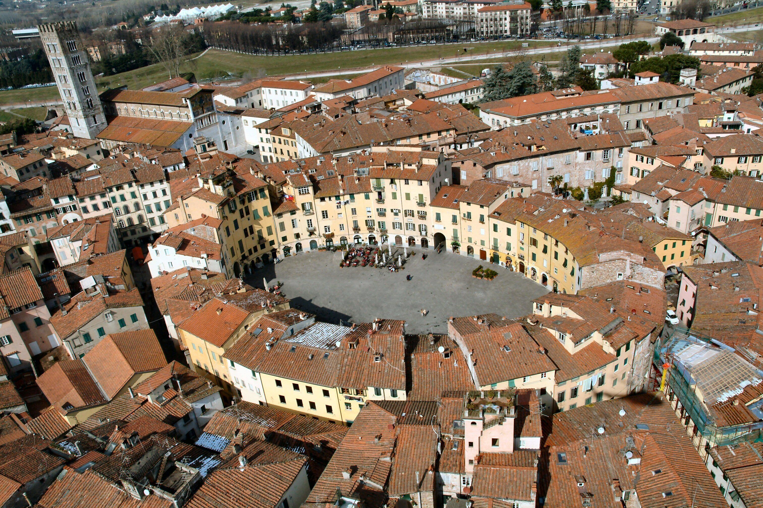 Eine Luftaufnahme des historischen Stadtzentrums mit einem zentralen Platz, umgebenden Gebäuden und einem markanten Turm.