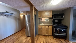 Cocina compacta con armarios de madera, refrigerador de acero inoxidable, estufa negra y encimera de madera.