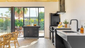 Een moderne keuken met een groot raam, een inbouwfornuis en een zwart aanrecht.