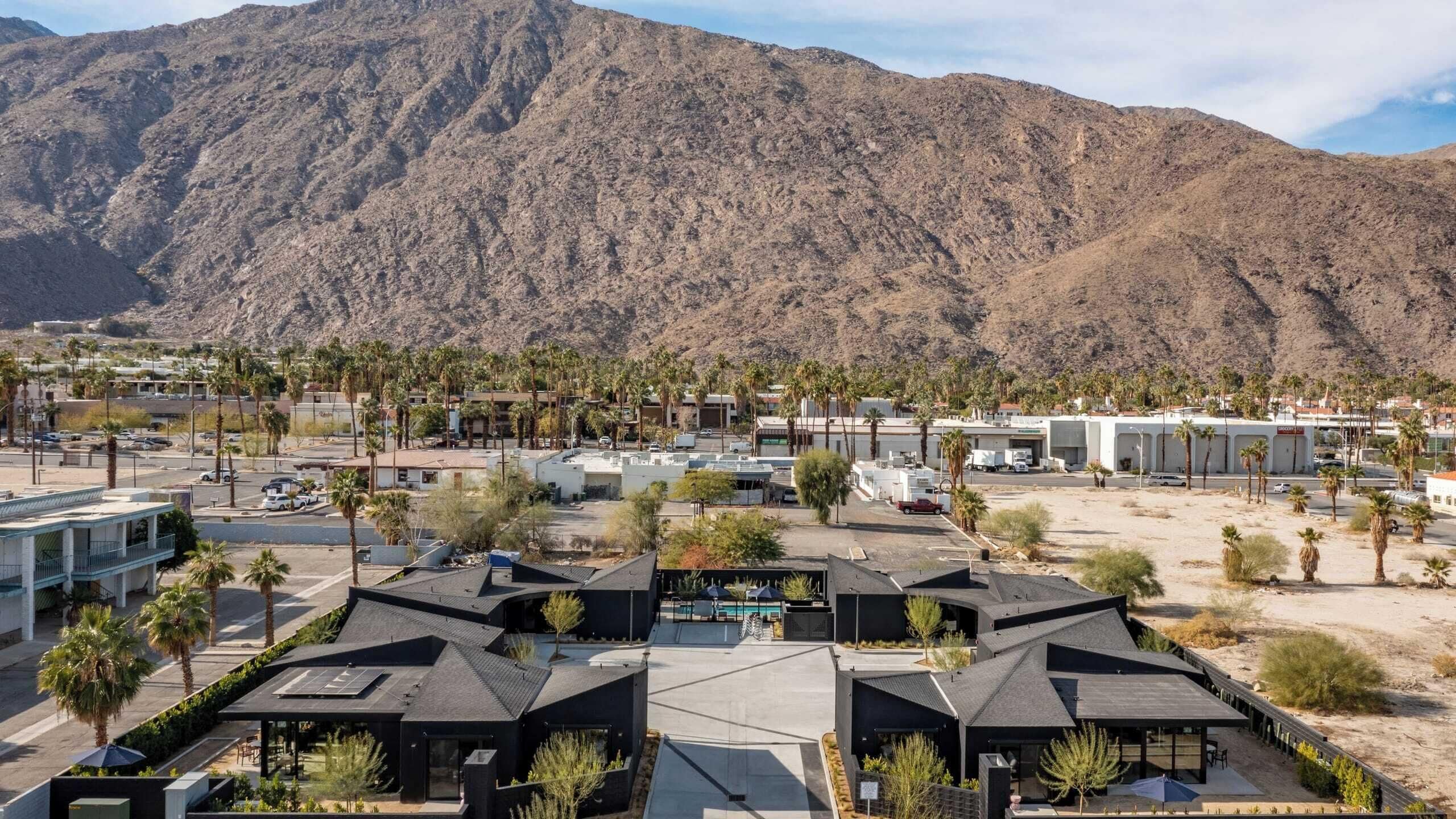 A modern resort with multiple buildings, a pool, and palm trees.