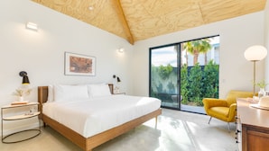 Een moderne slaapkamer met een groot bed, nachtkastjes, een bureau en een stoel.