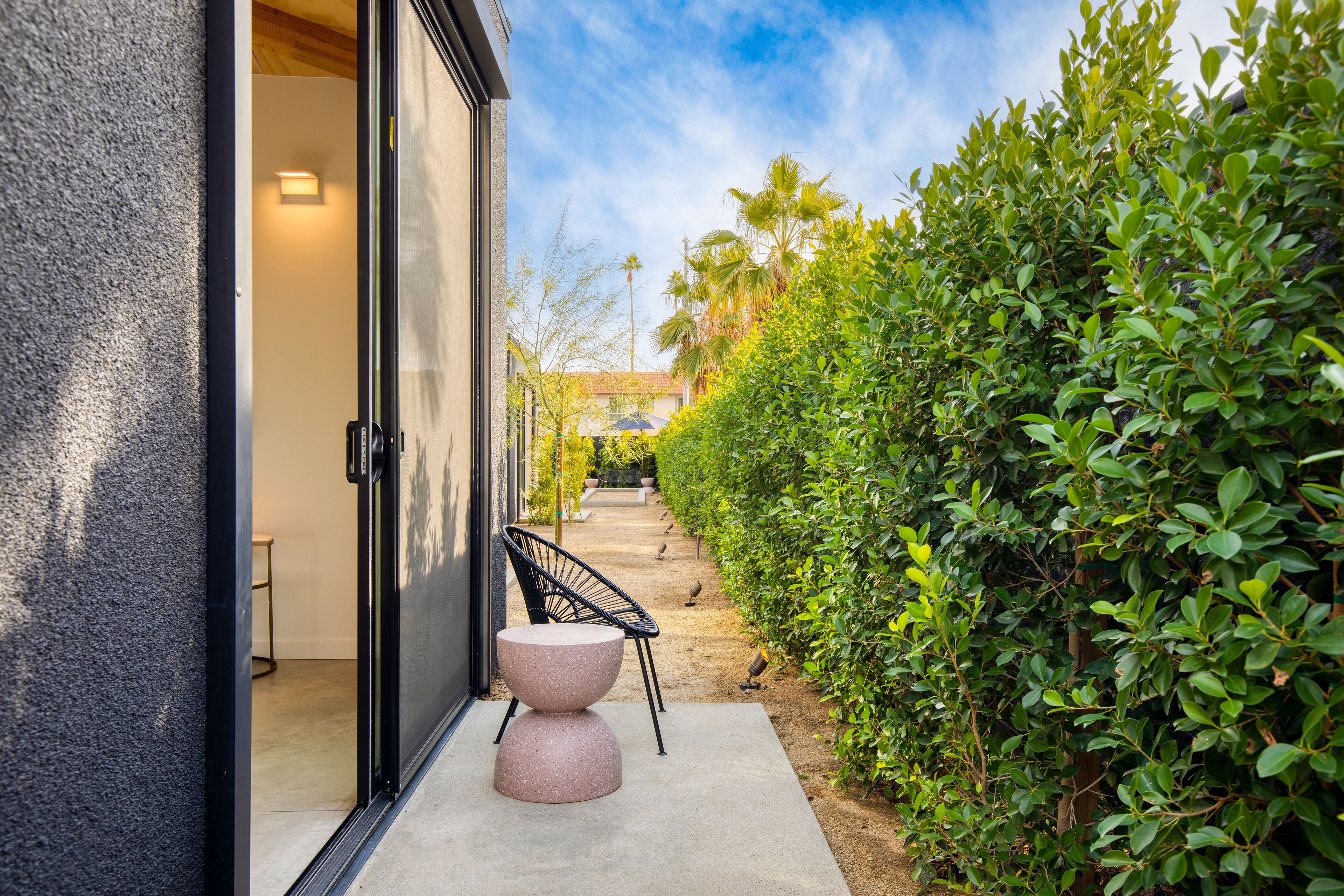 A modern building with a glass door, a concrete bench, and a well-maintained hedge.