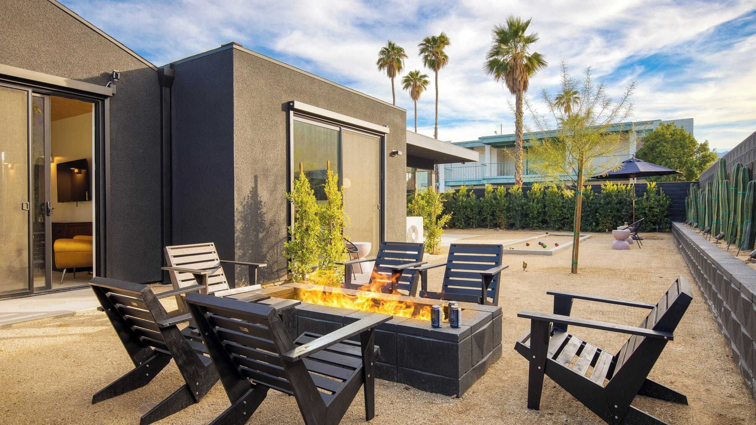 Un patio al aire libre con un brasero, asientos y vista a un edificio moderno.